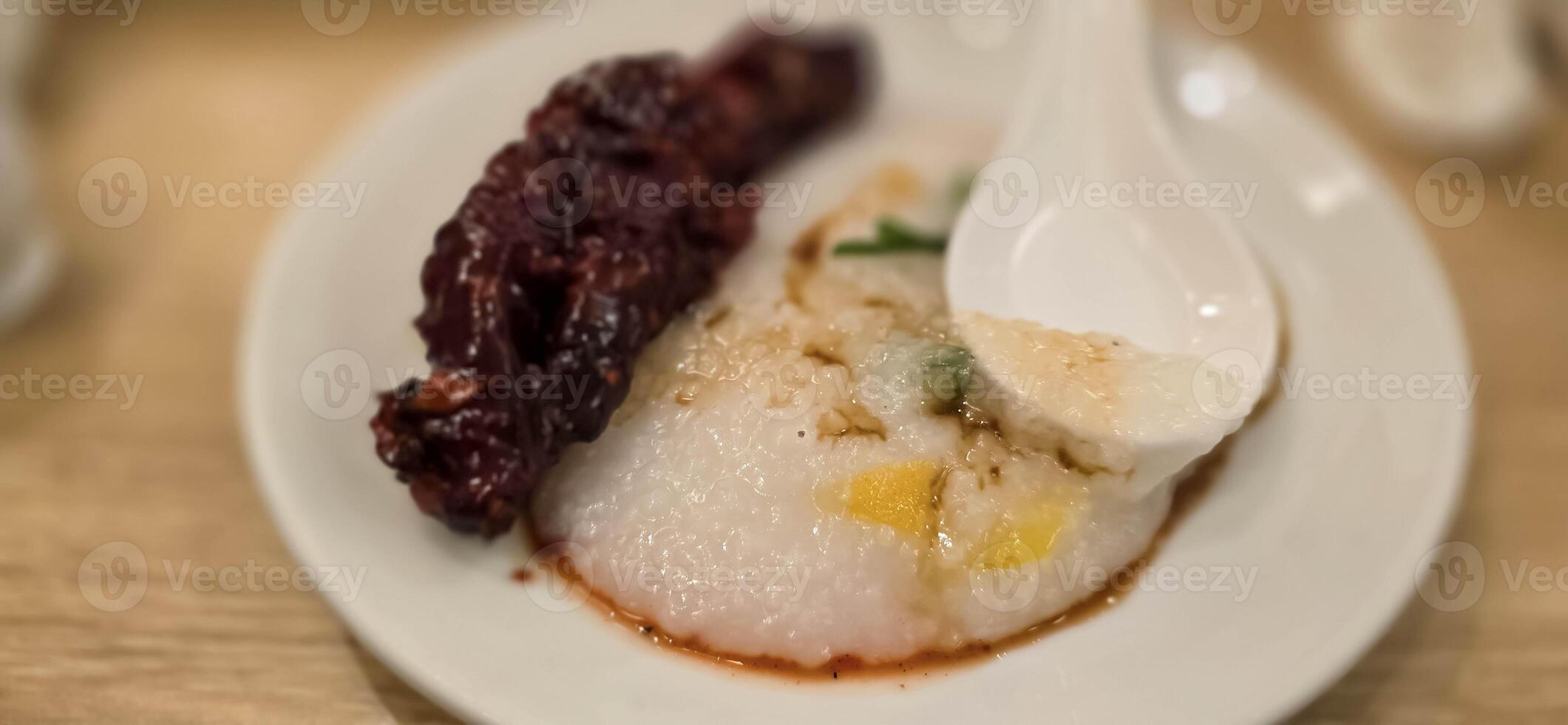 rice porridge with shredded chicken called bubur ayam served with crackers and sliced spring onion and others condiments photo