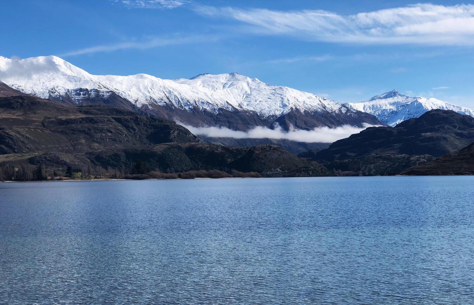 The mountain snow on top behind the lake photo