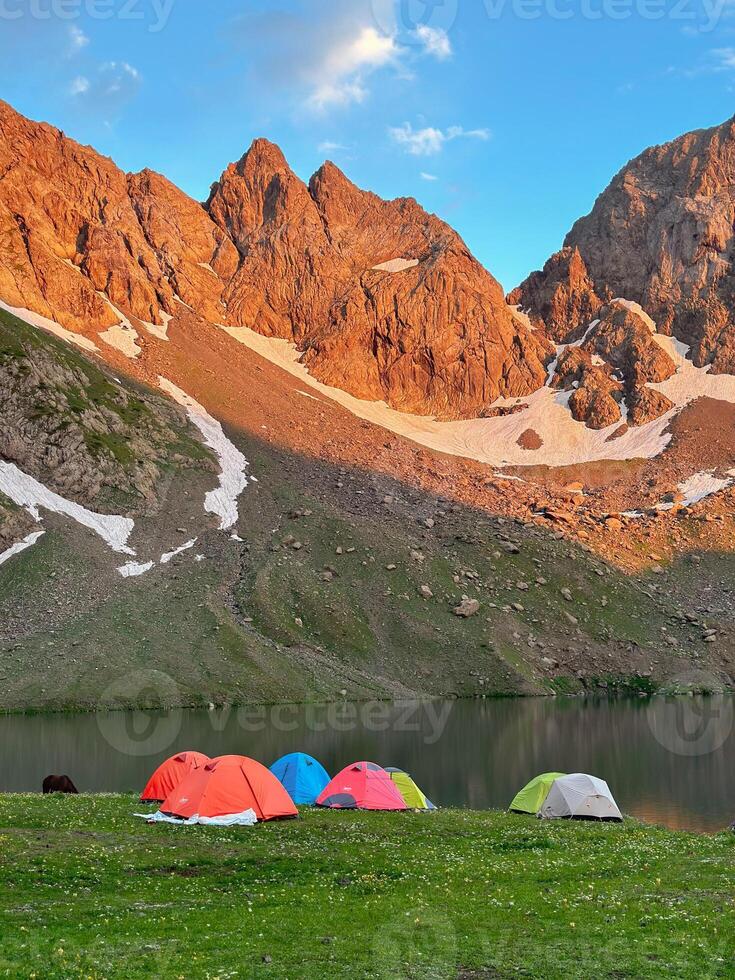 Camping tent by the lake in front of the mountain. photo