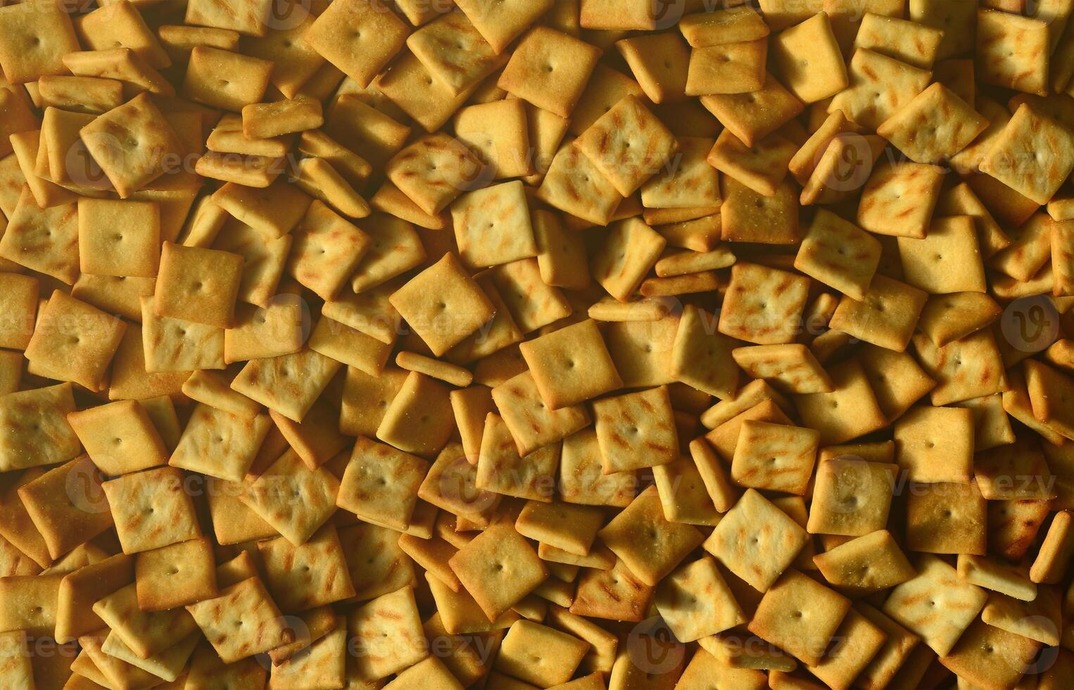 Background texture of small edible squares baked from dough and sprinkled with salt. A lot of salt cracker photo