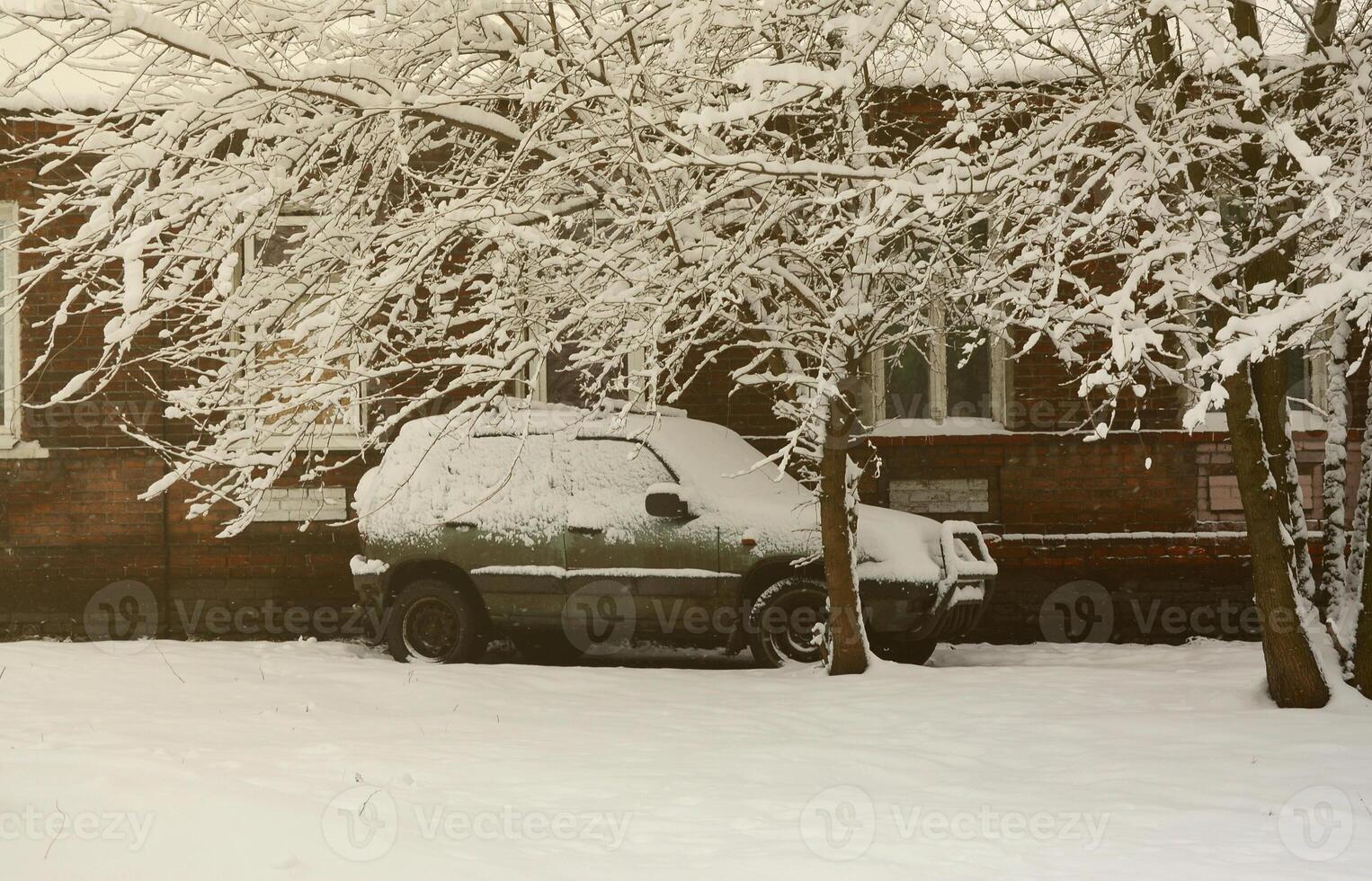 Photo of a car covered in a thick layer of snow. Consequences of heavy snowfall