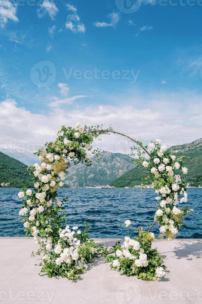 Round wedding arch stands on a pier by the sea photo