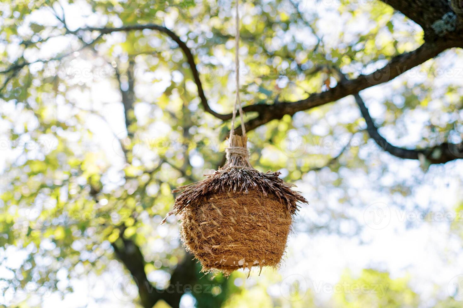 Wicker nest-house for birds hangs on a tree branch in the park photo