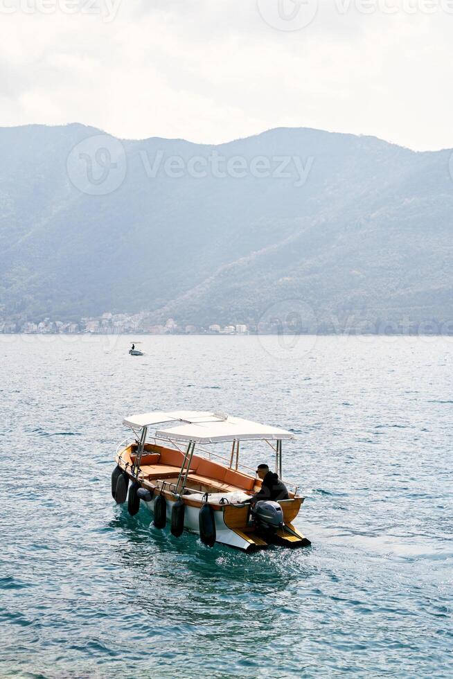 Man is sailing on a small excursion boat on the sea. Back view photo