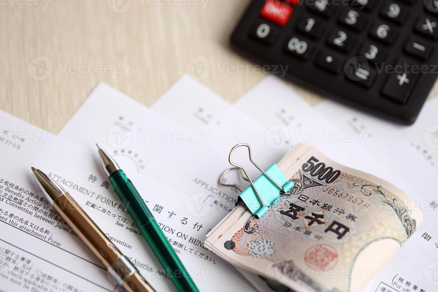 Japanese tax forms lies on table with calculator, pen and japanese yen money bills roll photo