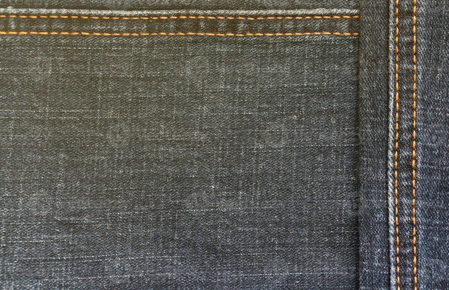 Detailed abstract texture of dark blue denim cloth. Background image of old used denim trousers fabric photo