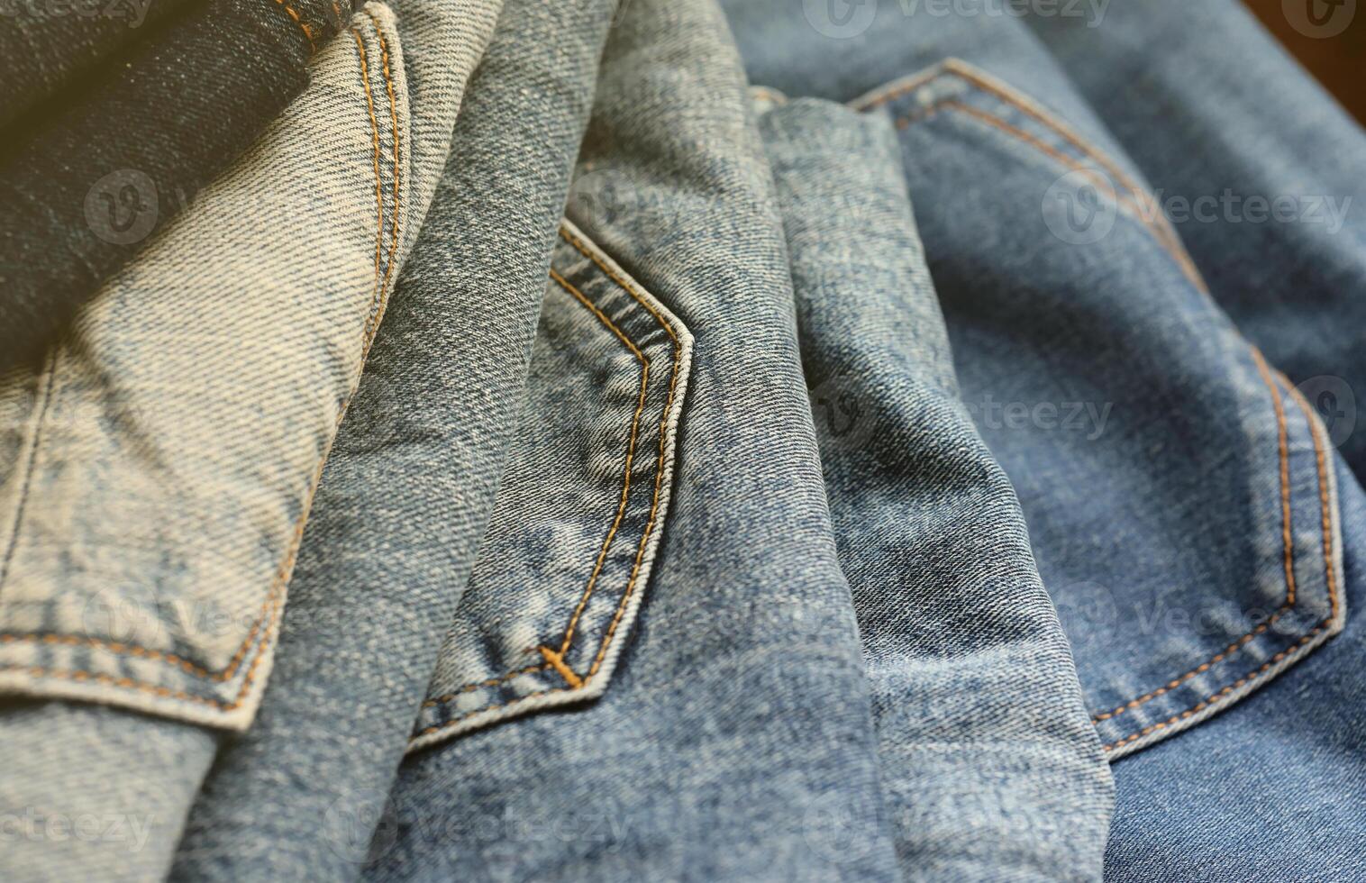 Many jeans in stack in wardrobe room. Row of pants denim jeans in closet. Concept of buy, sell, shopping and fashionable clothes photo