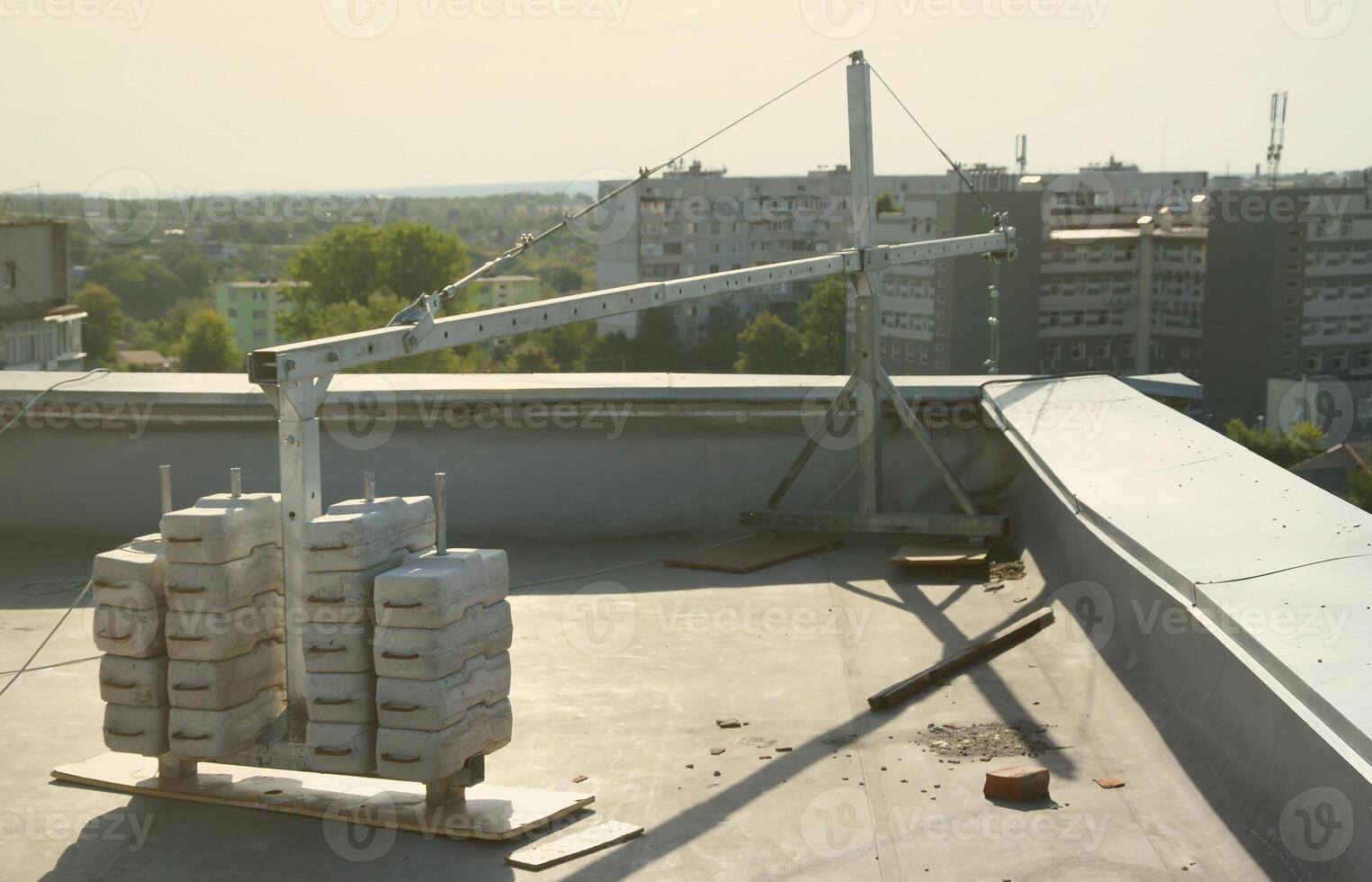 Counter weight or weight balance concrete blocks or bricks as part of suspended wire rope platform for facade works on high multistorey buildings. Many blocks with metal handles photo