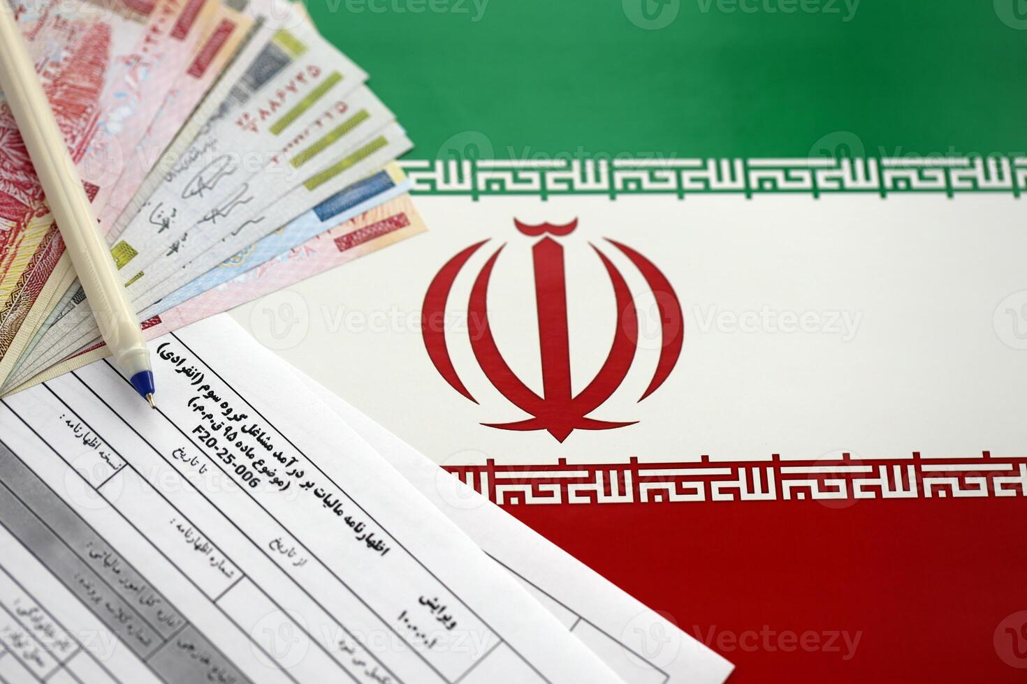 Iranian annual income tax return form F20-25-006 ready to fill on table with pen and iranian money on flag photo