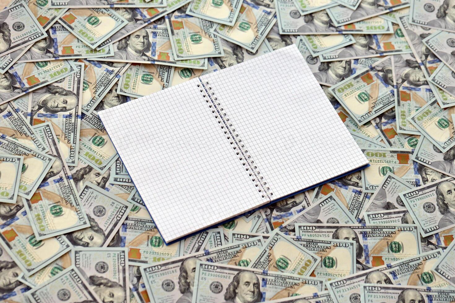 Office workplace table with blank notebook or notepad and many hundred dollar bills photo