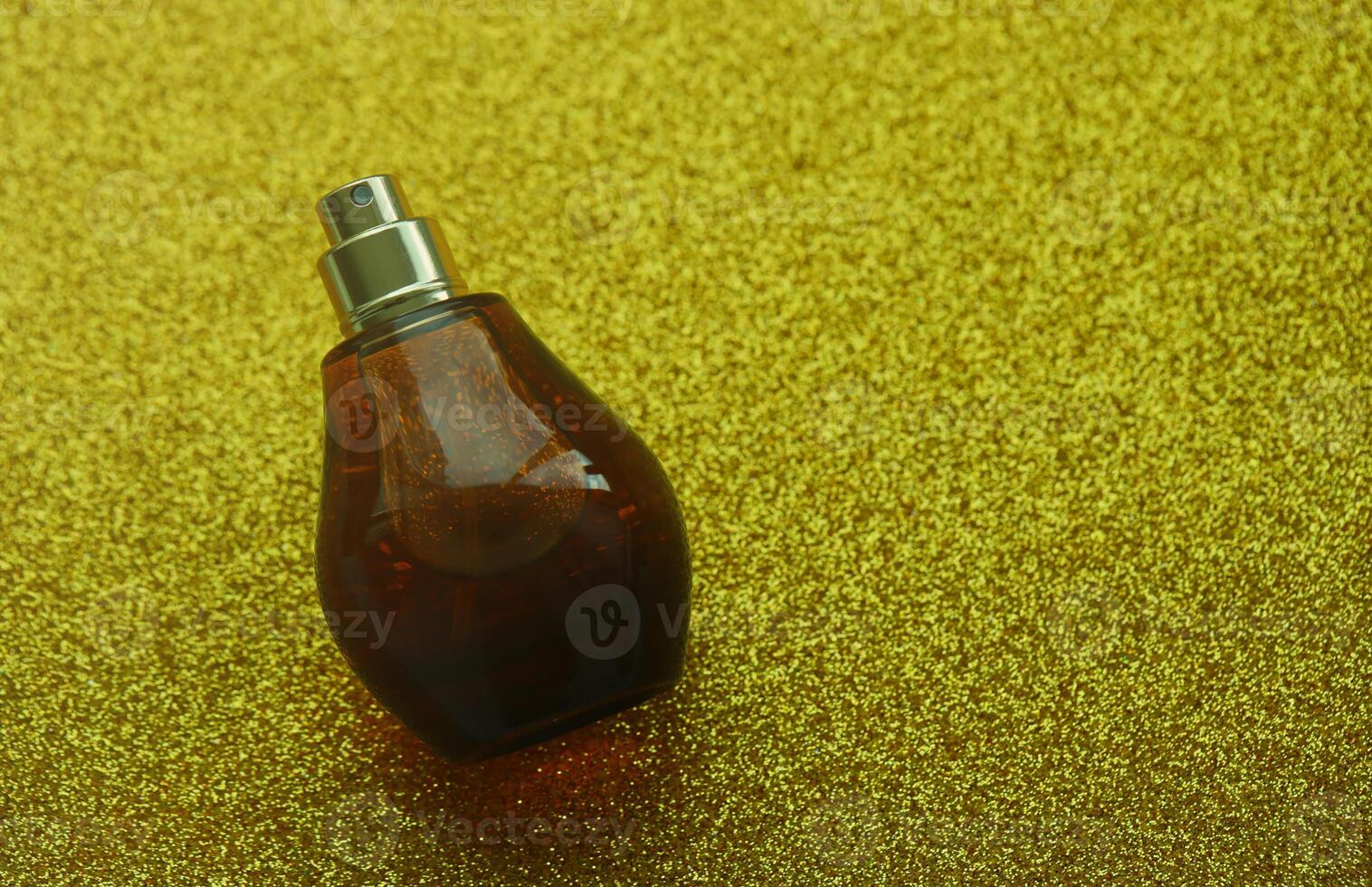 Women fragrance perfume bottle on yellow background close up. Unnamed blank sprayer bottle of perfume photo