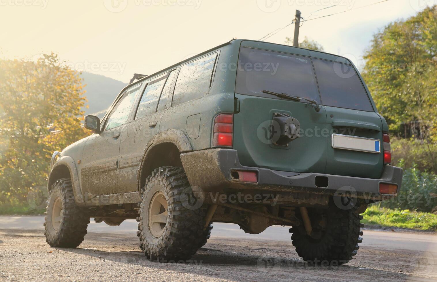 Automobile in a countryside landscape with a mud road. Off-road 4x4 suv automobile with ditry body after drive in muddy road photo