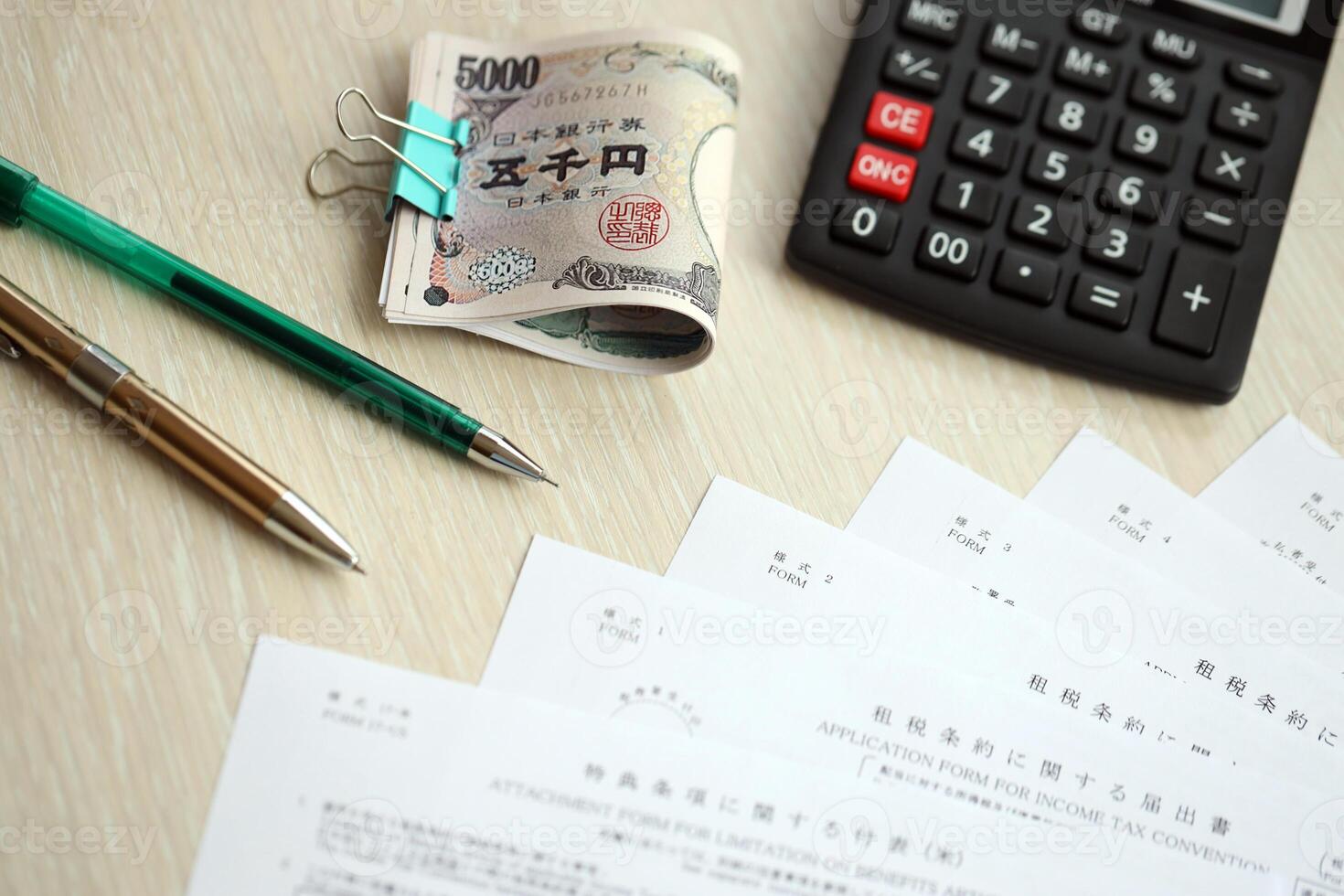 Japanese tax forms lies on table with calculator, pen and japanese yen money bills roll photo