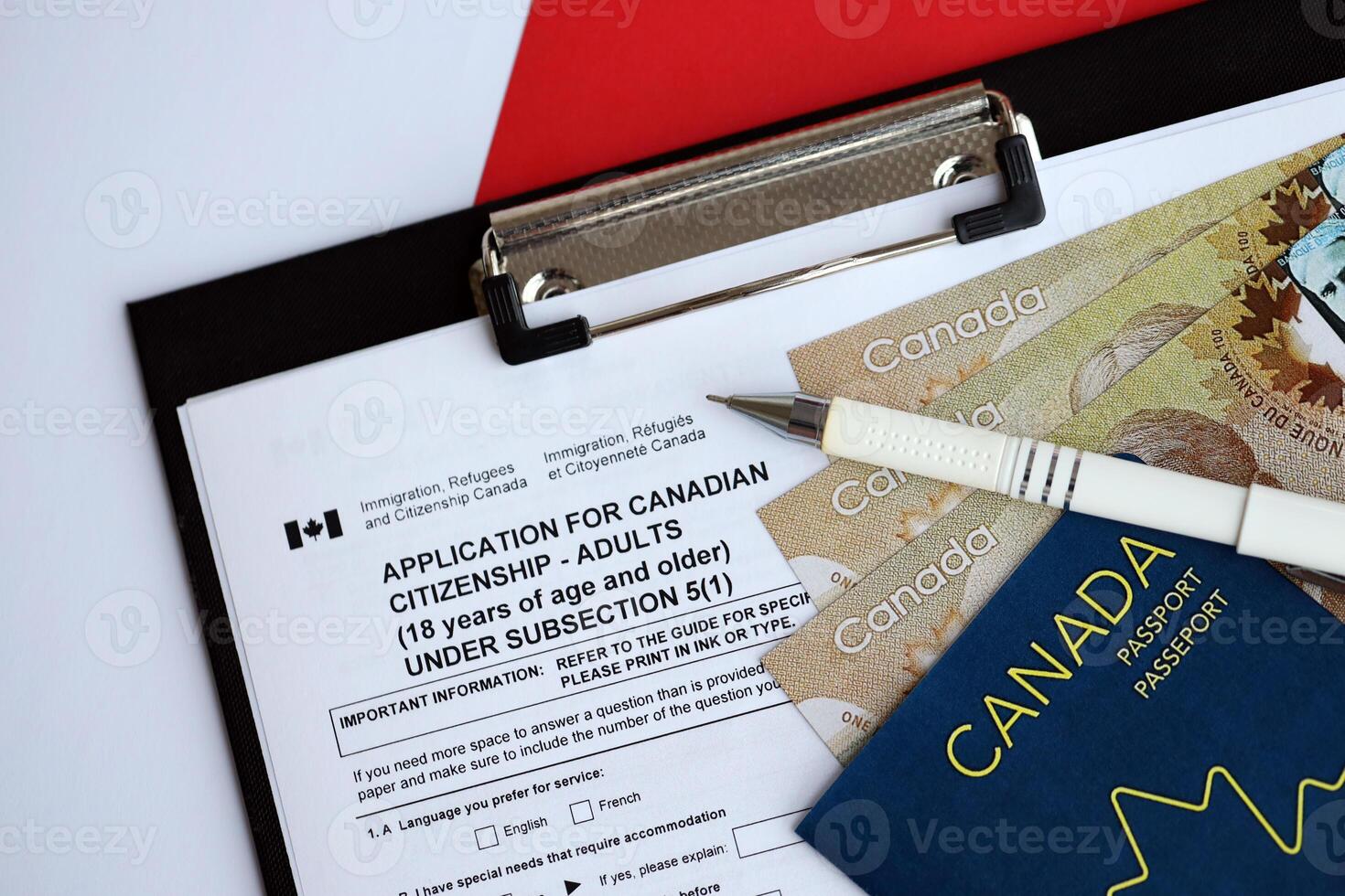 Application for Canadian citizenship for adults on table with pen, passport and dollar bills photo