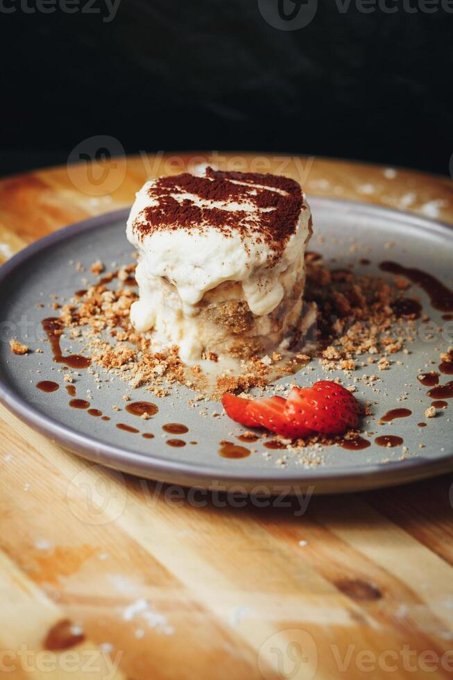 Delectable Tiramisu Served on a Ceramic Plate Garnished With Strawberry and Cocoa photo