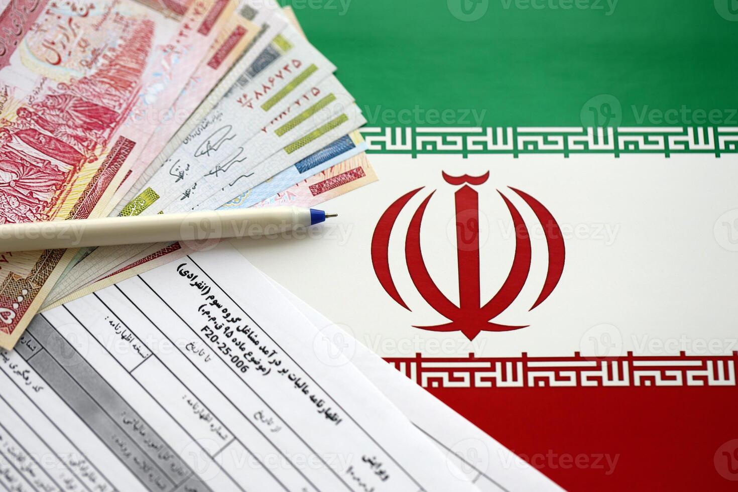 Iranian annual income tax return form F20-25-006 ready to fill on table with pen and iranian money on flag photo