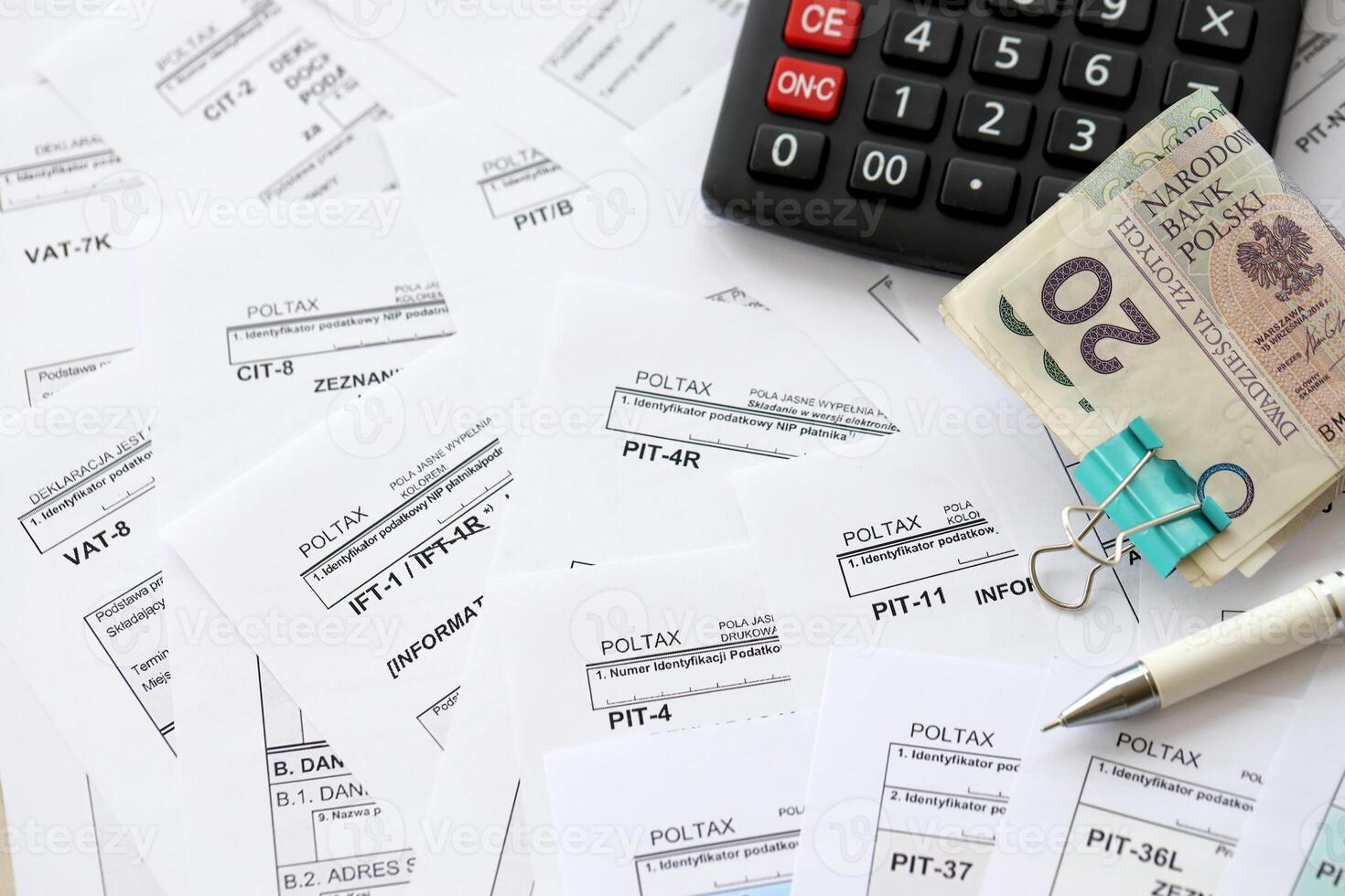 Polish zloty money PLN, calculator and pen on big amount of polish PIT, CIT and VAT tax forms close up. Accounting, bureaucracy and taxpayers routine photo