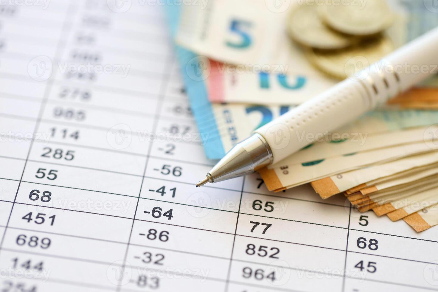 Business concept with many euro money bills and pen on schedules with calculations photo