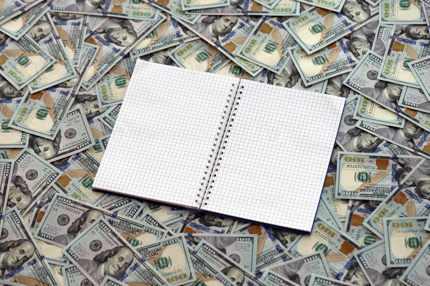 Office workplace table with blank notebook or notepad and many hundred dollar bills photo