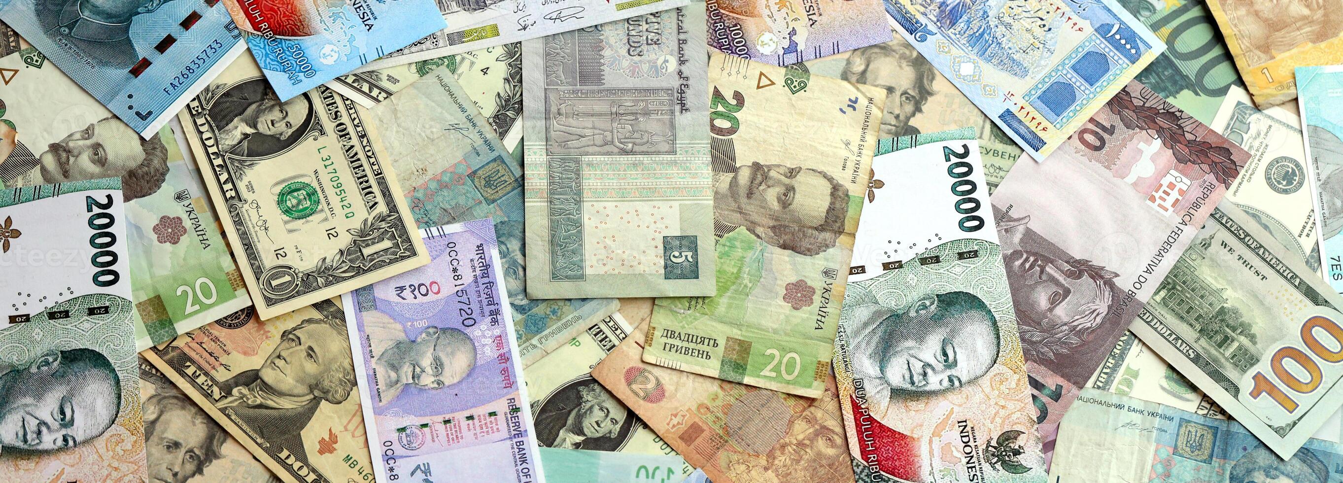 Many banknotes of different currency. Background of big amount of random money bills photo