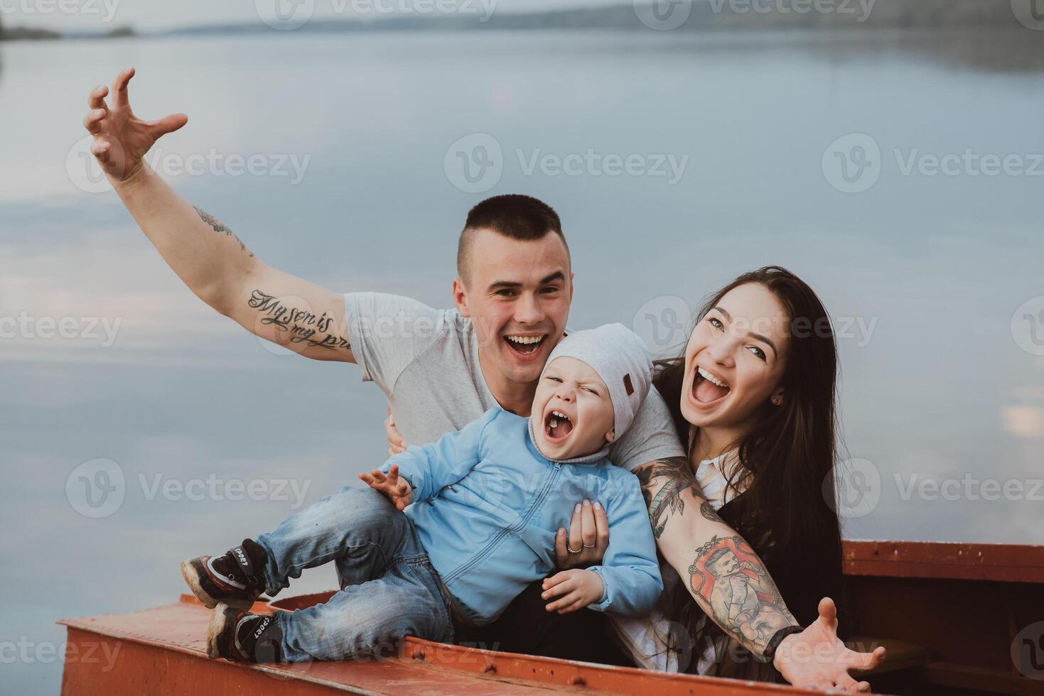 young happy family with their son sit and smile in a boat by the water photo