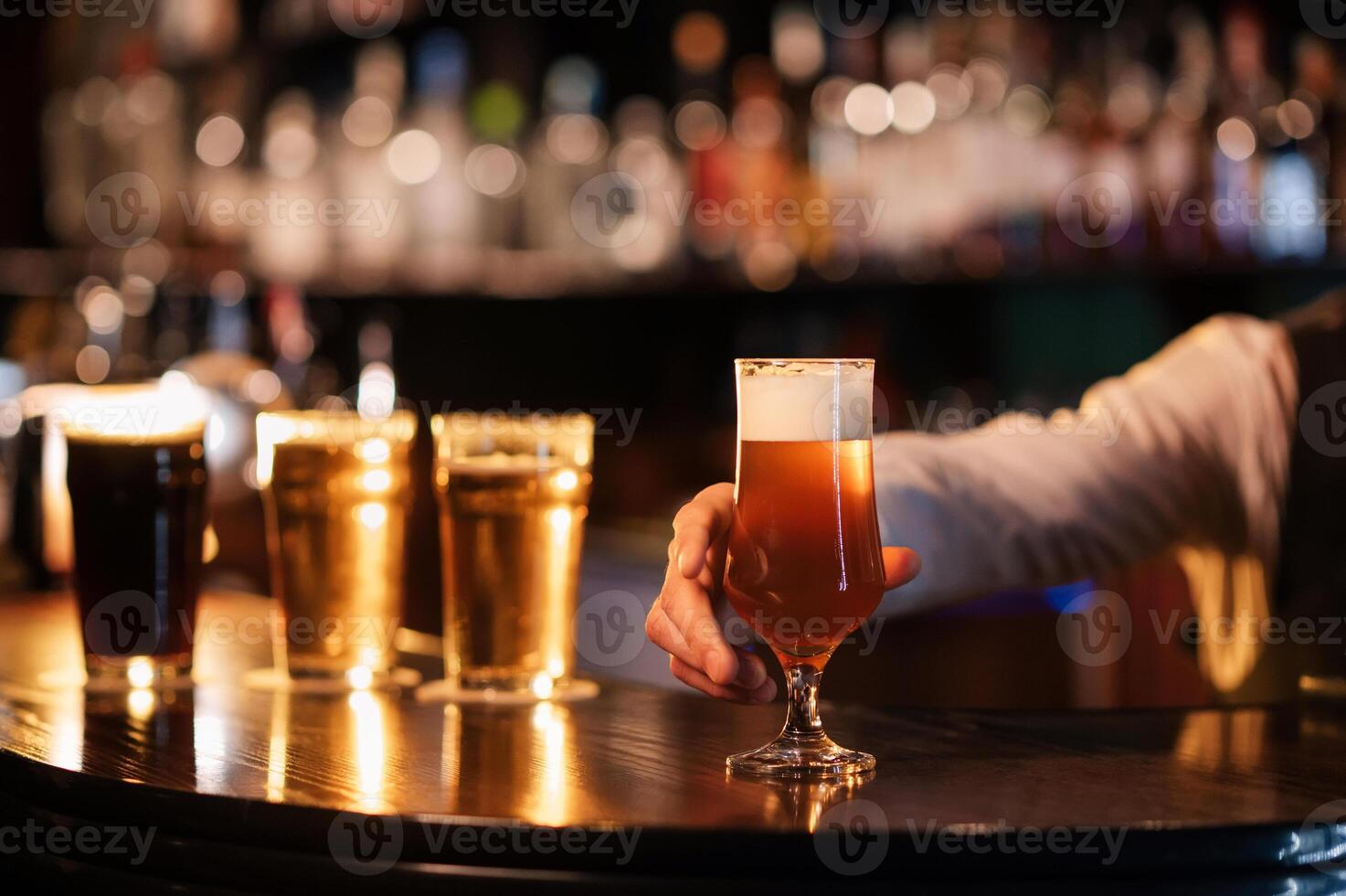 bartender hands a glass of tulip frothy draft beer to the bar photo