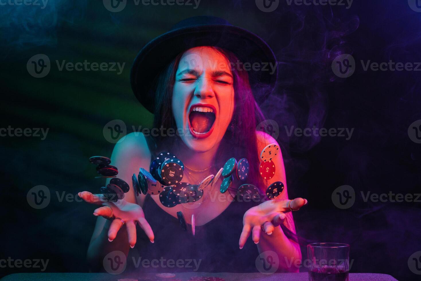 Playing poker and gambling in casino. Emotional girl throws up chips photo