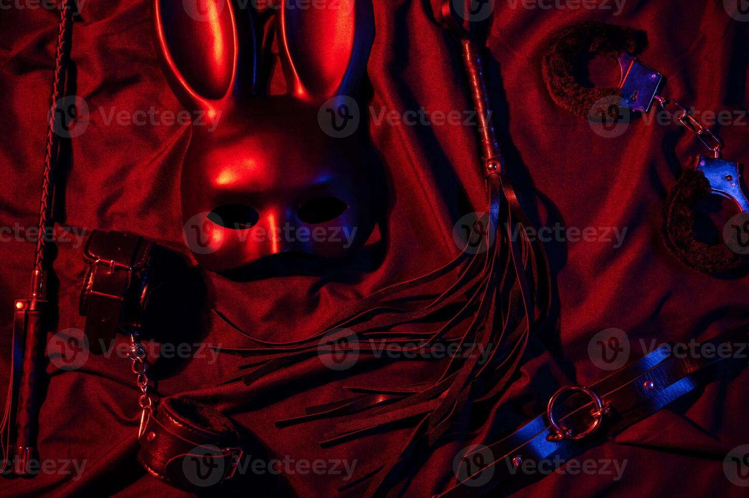 Erotic sex toys for adults for BDSM sex with submission and domination. Handcuffs, mask and leather flogger whip on a black background photo