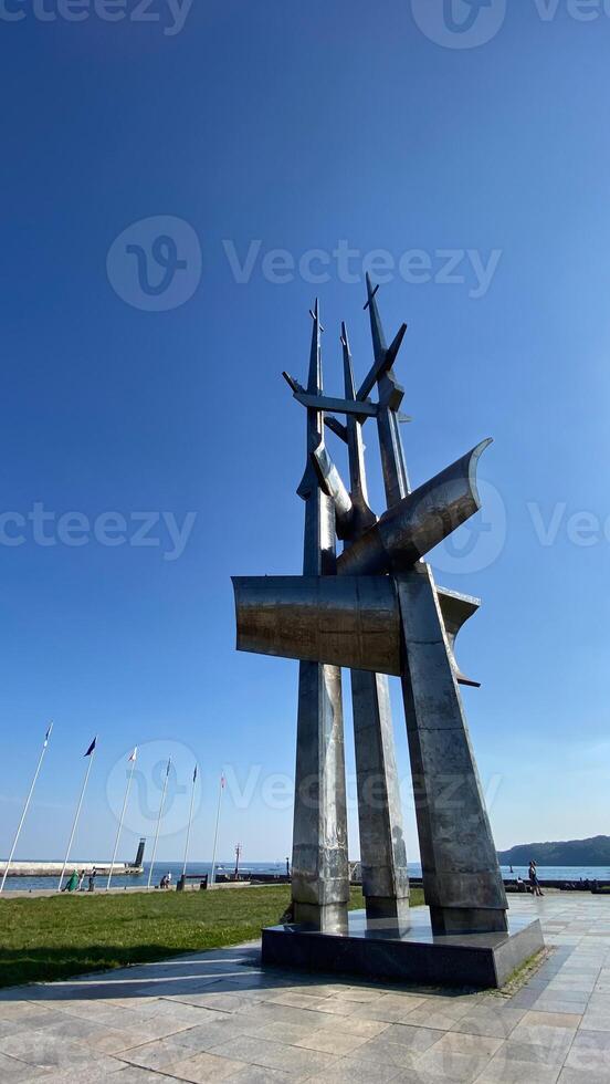 Modern metal monument against a clear blue sky in a coastal park. An impressive structure symbolizing strength and achievement photo