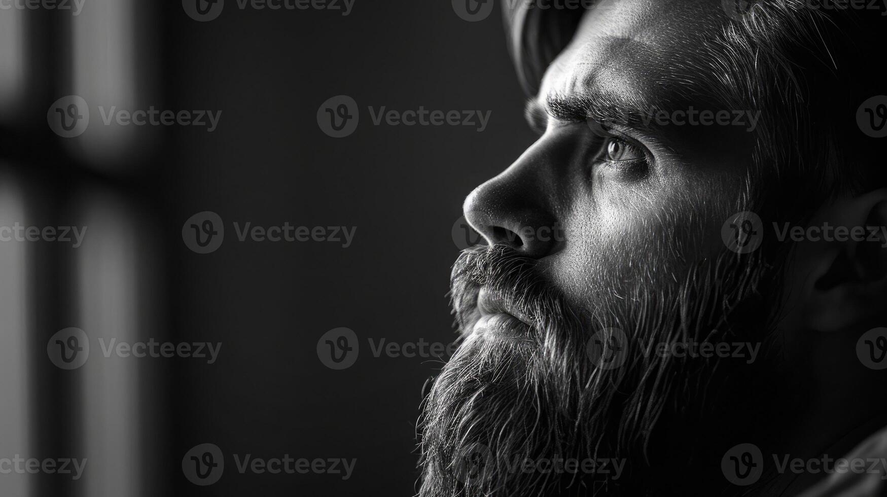Moody black and white portrait of a bearded man, thoughtfully gazing into the distance photo