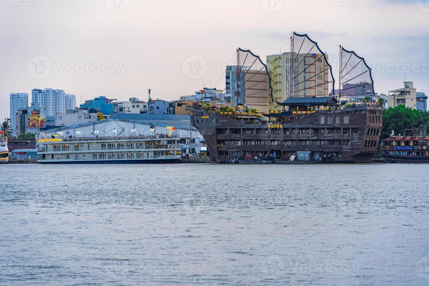 Sunset view of Bitexco Tower, buildings, roads, Bason bridge and Saigon river in Ho Chi Minh city, container cargo ship on Saigon river. Travel concept. photo