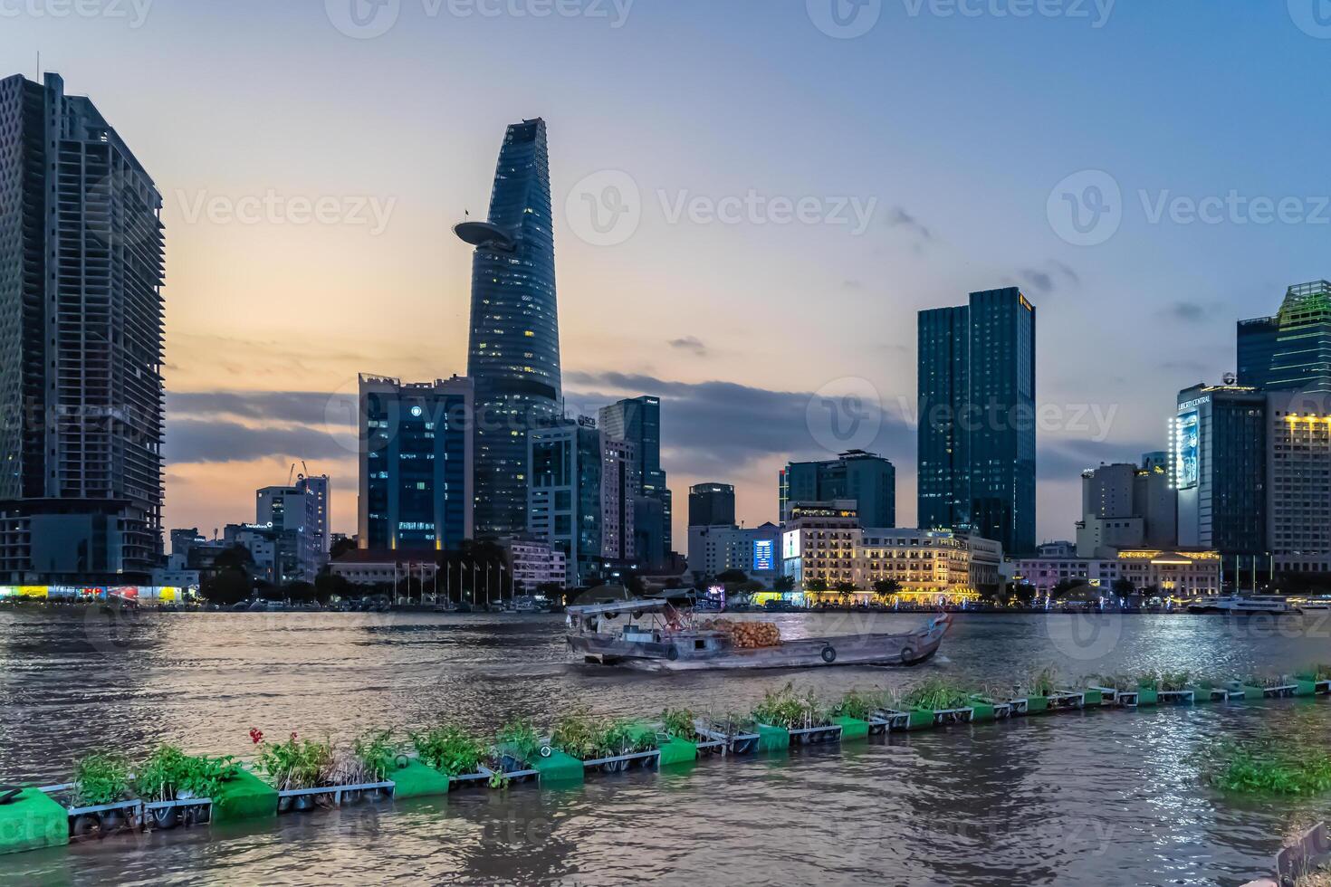 Sunset view of Bitexco Tower, buildings, roads, Bason bridge and Saigon river in Ho Chi Minh city, container cargo ship on Saigon river. Travel concept. photo