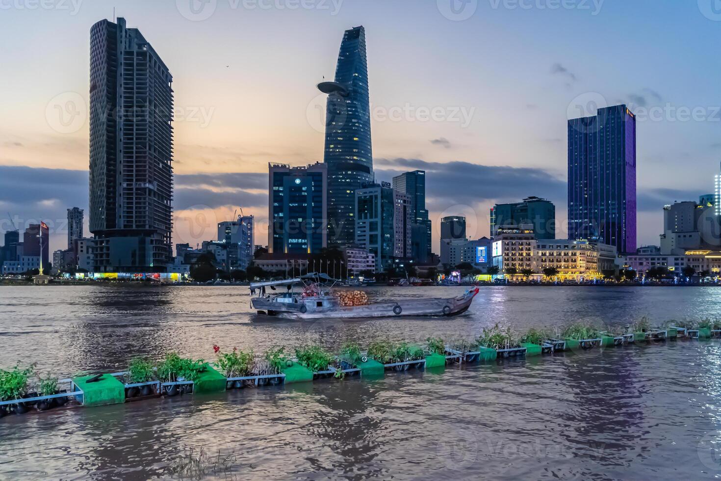 Sunset view of Bitexco Tower, buildings, roads, Bason bridge and Saigon river in Ho Chi Minh city, container cargo ship on Saigon river. Travel concept. photo