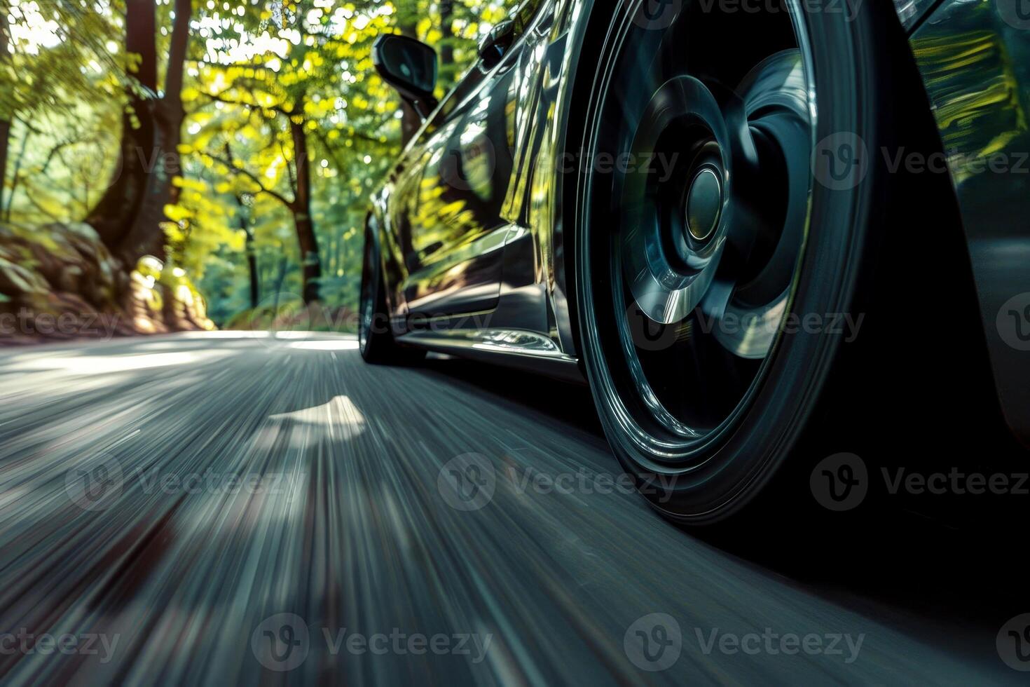 close up tire car is speeding down a road with trees in the background. photo