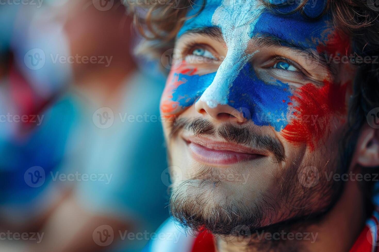 A joyful French man with his face painted in the blue white and red colors of the France flag, cheering at a football match, with a blurred stadium background. photo
