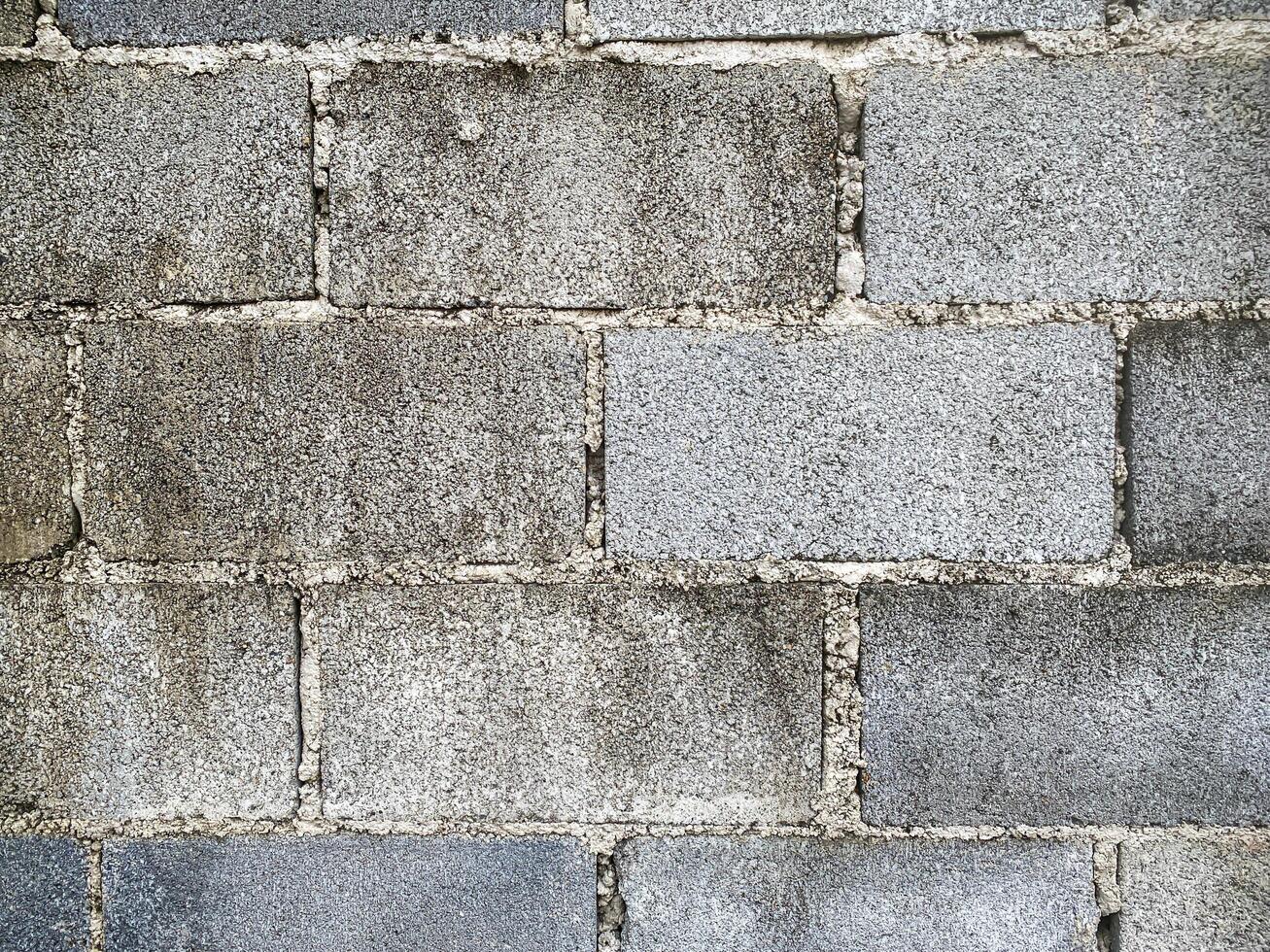 A white wall with a hole in it. The wall is cracked and has a rough texture photo