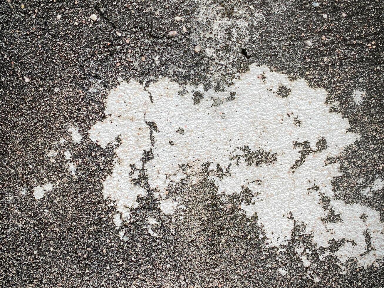 A white wall with a hole in it. The wall is cracked and has a rough texture photo