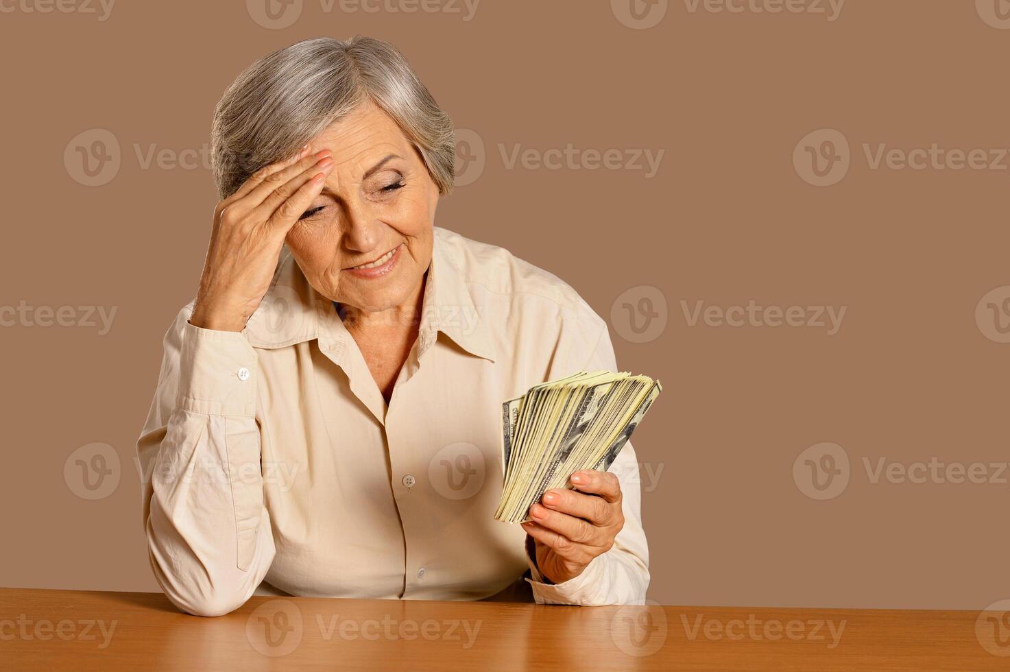Happy beautiful elderly woman with dollars on background photo