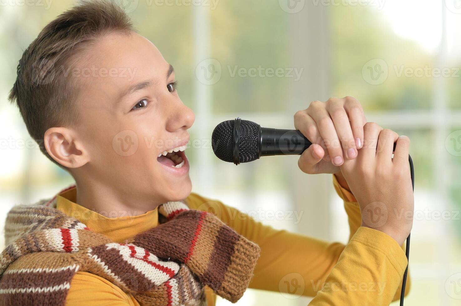 Cute young boy singing into a microphone photo