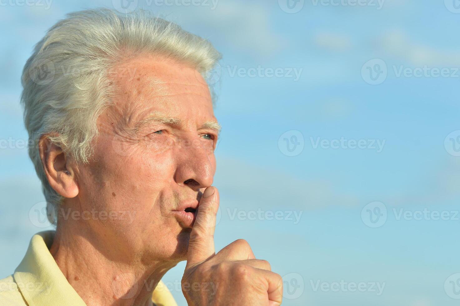 Elderly man put his finger to his lips photo