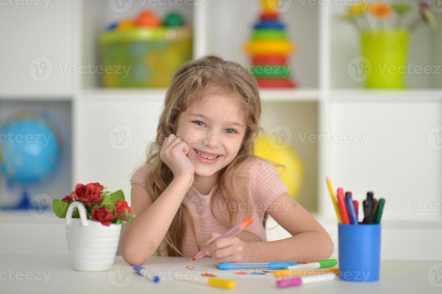 cute girl in the nursery draws at the table photo