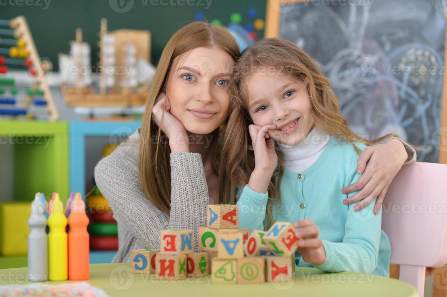 Portrait of little girl and her mother playing photo