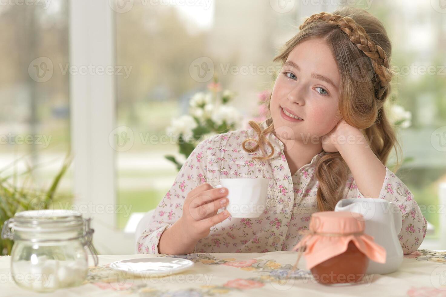 Smiling little girl holding big cup of tea photo