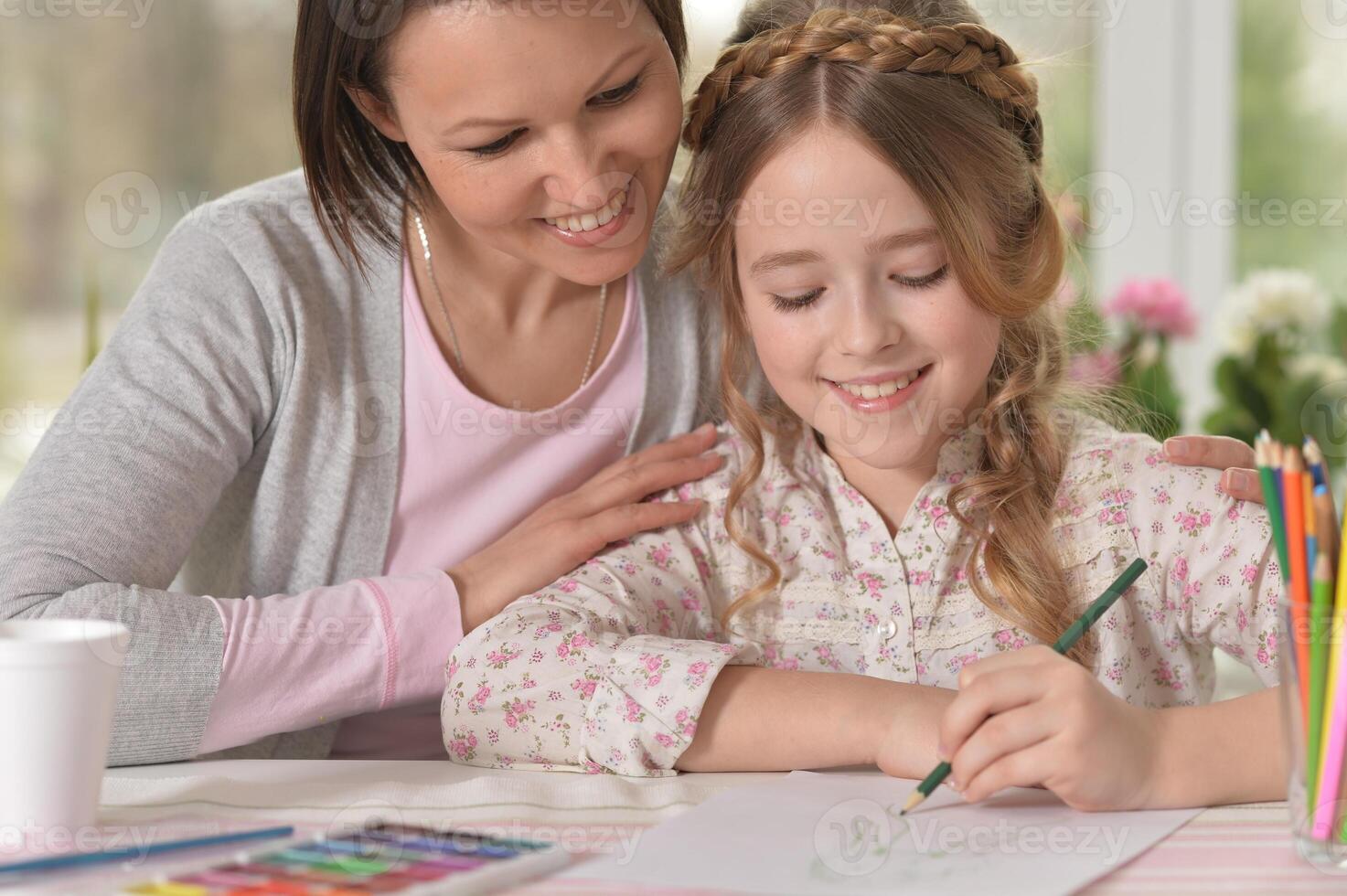 Cute mother and daughter drawing with pencils photo