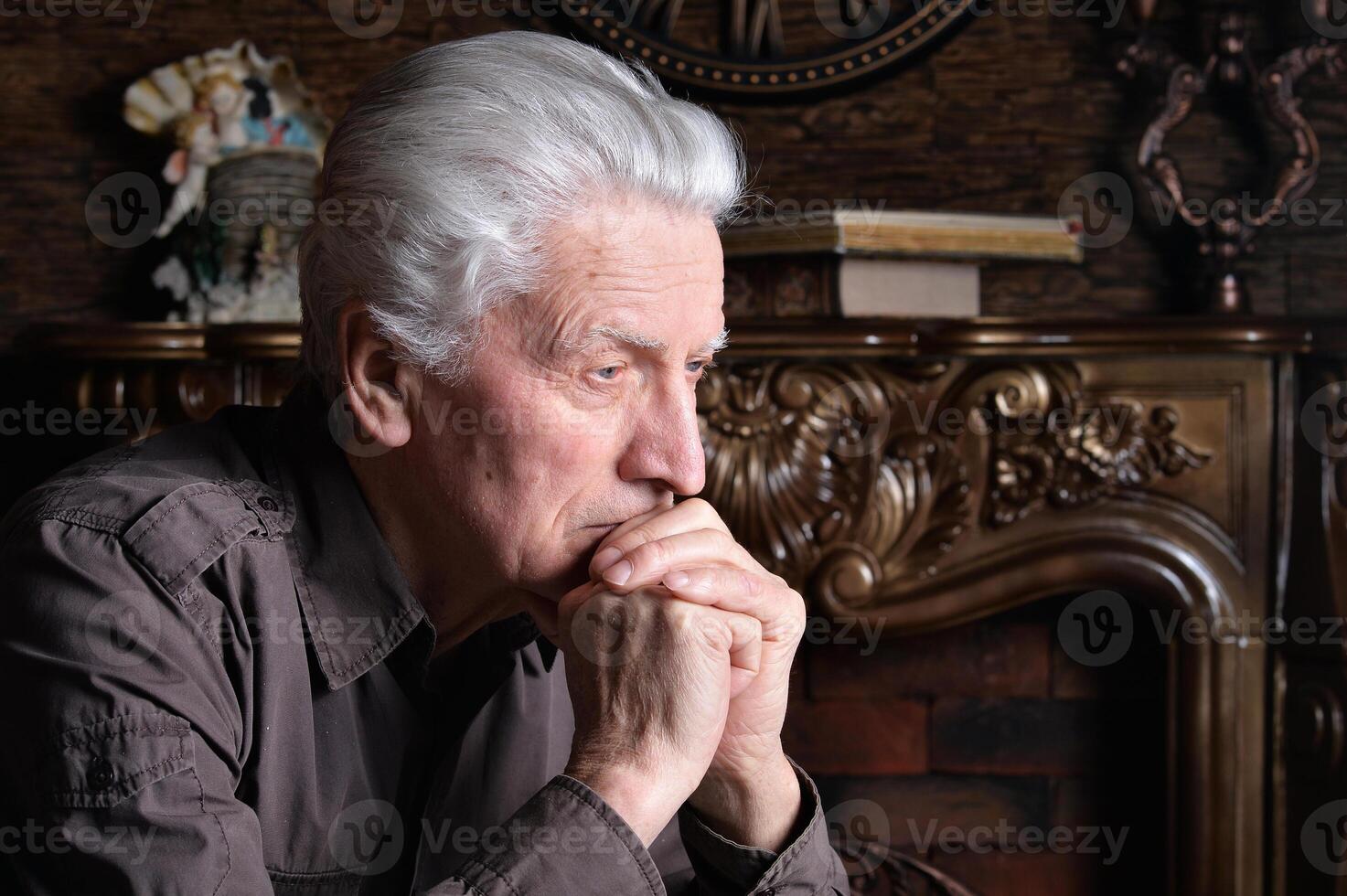Portrait of elderly sad man sitting at home photo