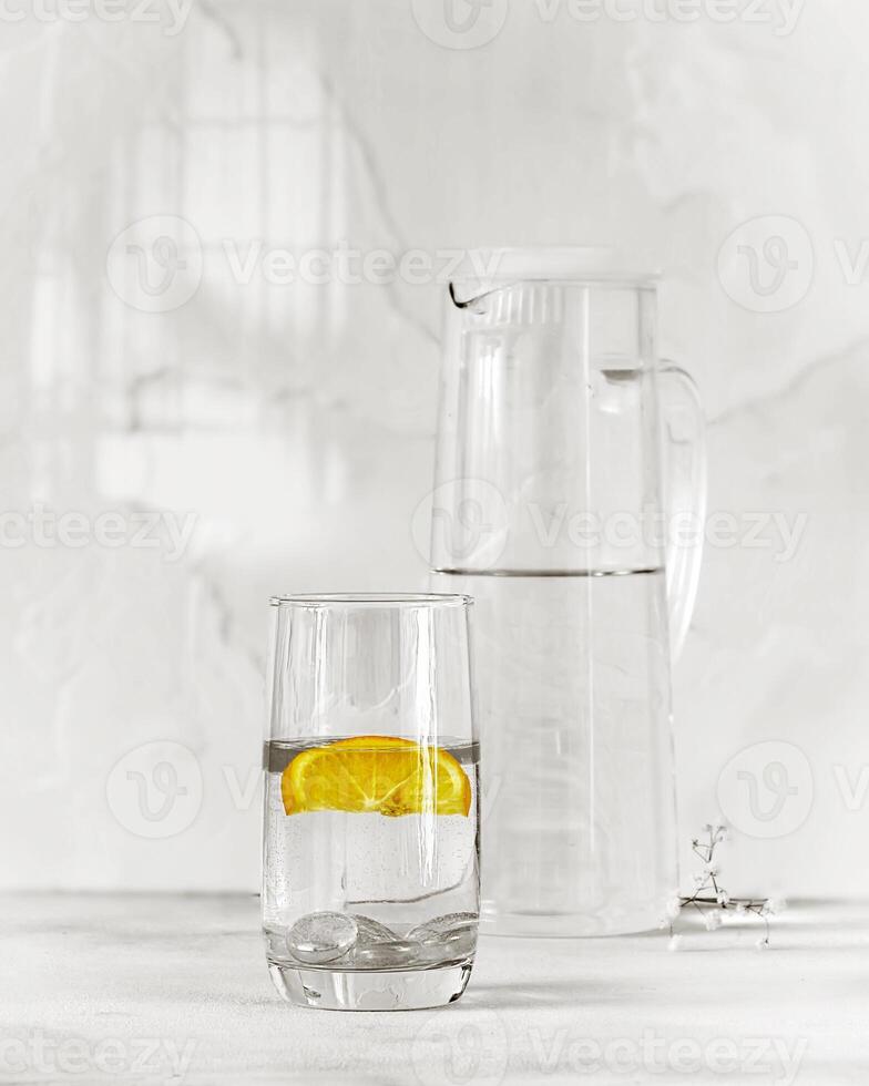 Black and white food photo of a glass of cold water with yellow lemon slice