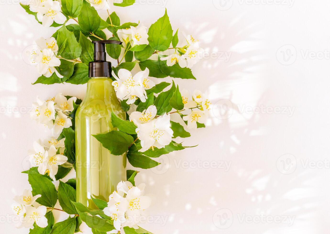 Bottle for branding and label on a blooming Jasmin branch with sun glare photo
