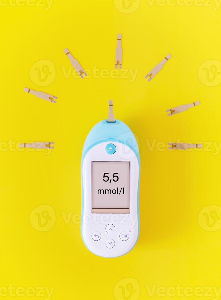 A blood glucose meter with test strips in the form of sunlight on a bright yellow background photo