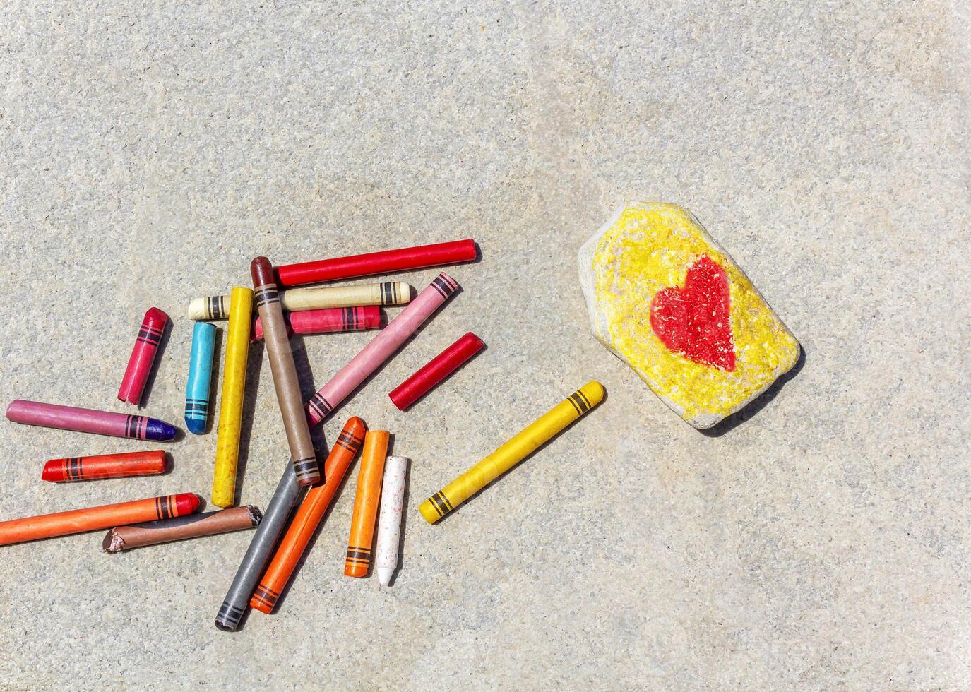 A red heart symbol is drawn on a a pebble outside with chalk photo