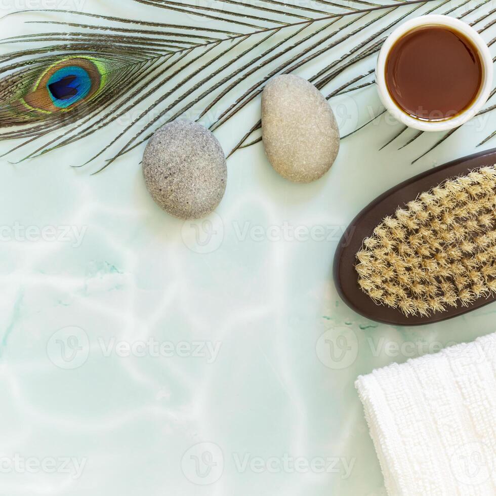 Flat lay composition with peacock feather, massage stones, oil, towel and body brush photo